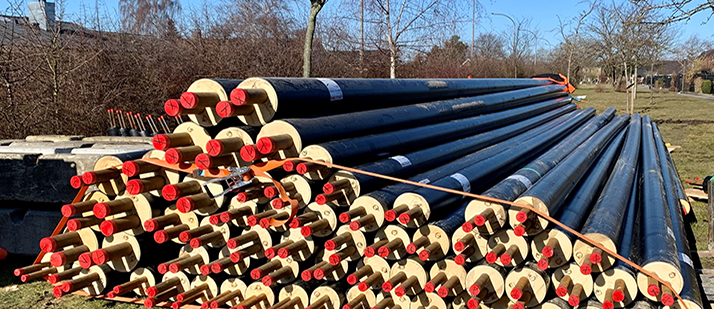 Fjernvarmerør ligger i en bunke på en græsplæne.